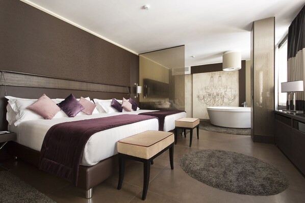 A modern hotel room with a large bed, a separate bathroom, and a small seating area.