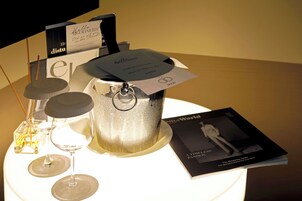 A table with a decorative container, a wine glass, a candle, and a book.