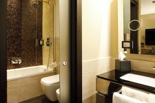 Ein modernes Badezimmer mit einer Duschkabine aus Glas, einer weißen Toilette und einer schwarzen Ablage mit Waschbecken und Spiegel.