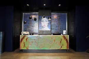 A reception desk with a marble top, overhead lighting, and framed artwork on the wall.