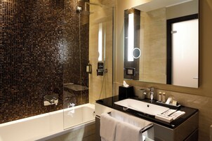 A modern bathroom with a glass-enclosed shower, a large mirror, and a black countertop with a white sink.
