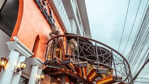 Exterior de un hotel con fachada curva, terraza de madera y escalera espiral con barandilla de metal.