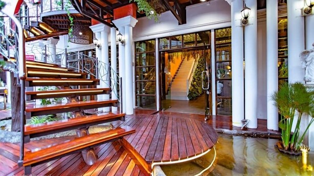 Una escalera de madera que lleva a un espacio cubierto con vista al acceso de un edificio.