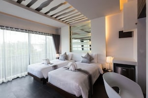 Une chambre d’hôtel moderne dotée de deux lits, d’une grande fenêtre avec rideaux, d’une baignoire intégrée et d’un design de plafond original.