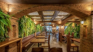 Un restaurante con paredes de ladrillo, mesas de madera y plantas verdes.