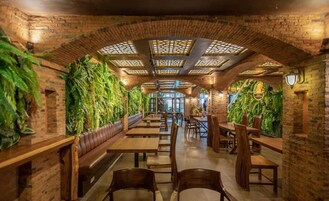 Un restaurant aux murs de briques, aux tables en bois et agrémenté de plantes vertes.