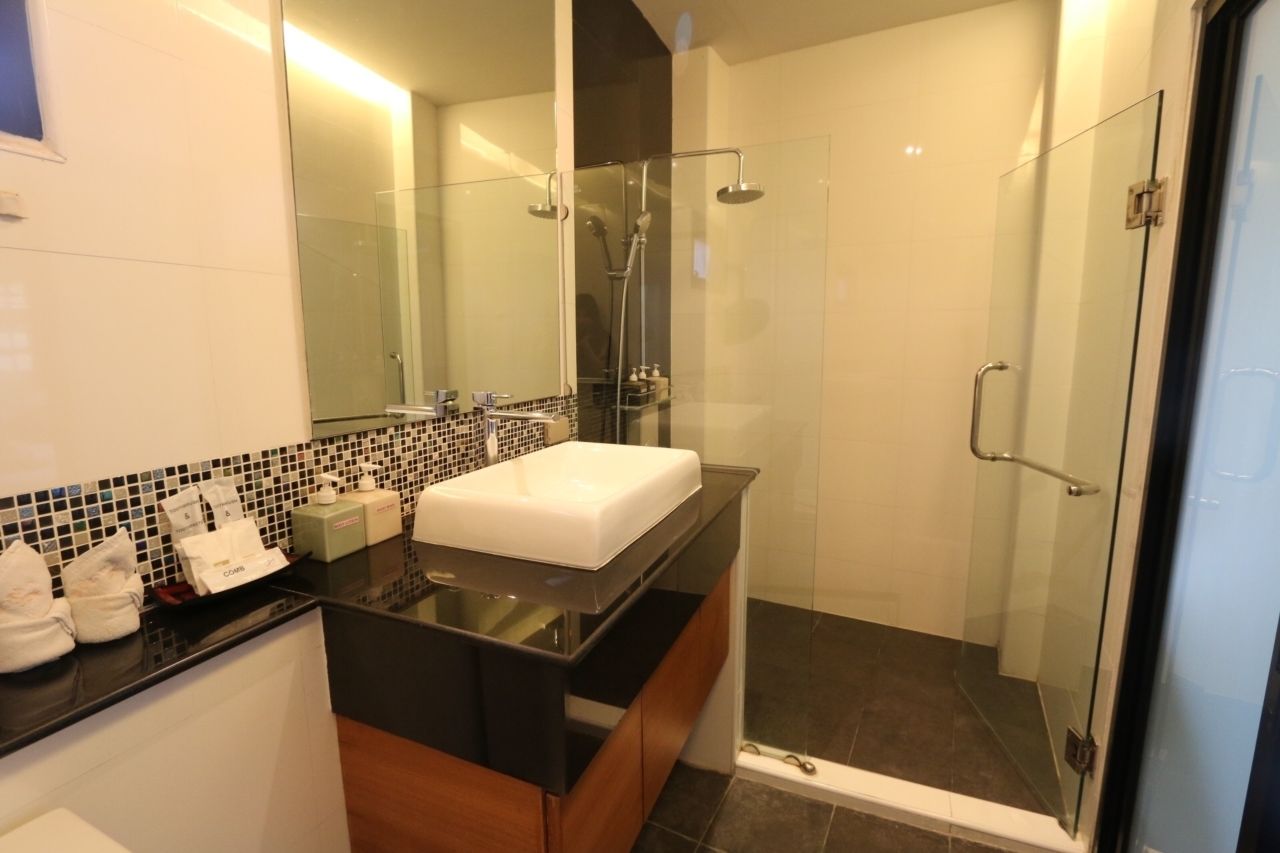 A modern bathroom with a glass-enclosed shower, a black countertop, and a white sink.