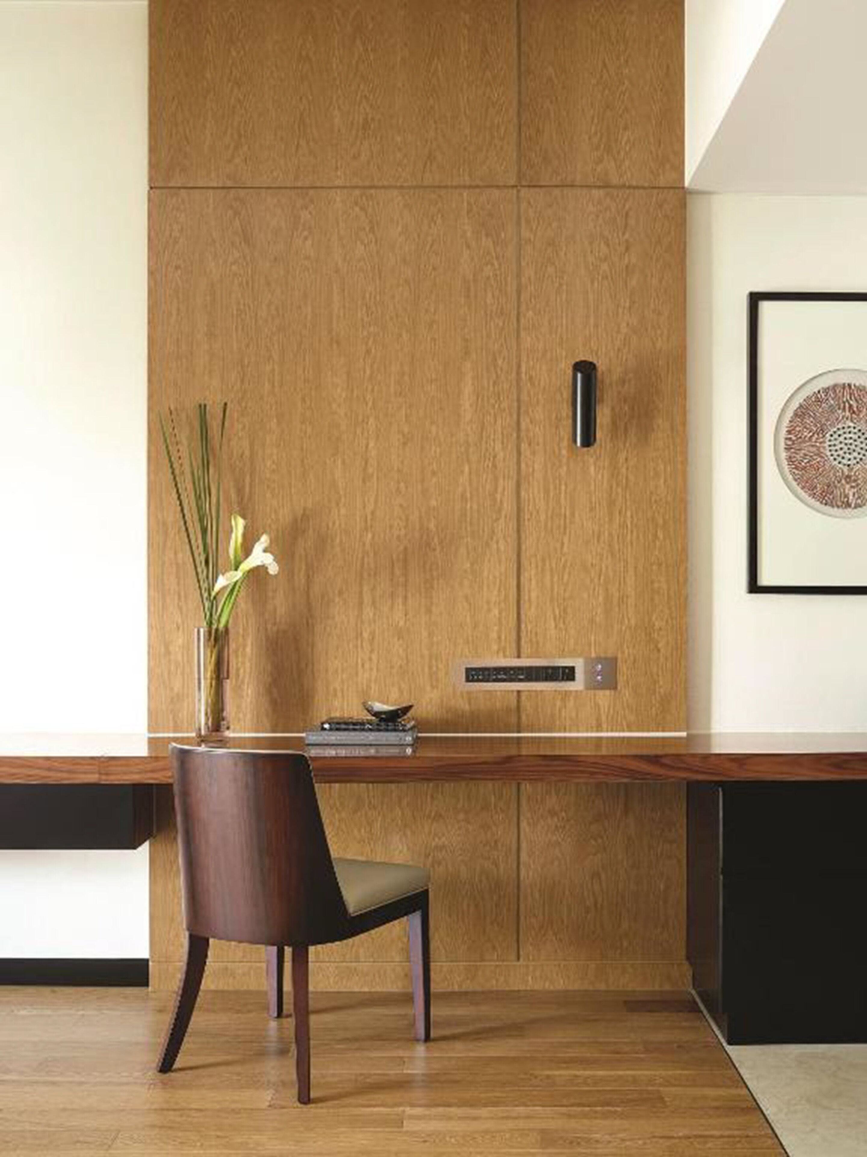 Une cuisine moderne avec des meubles en bois, une cuisinière encastrée et un vase rempli de fleurs posé sur le plan de travail.