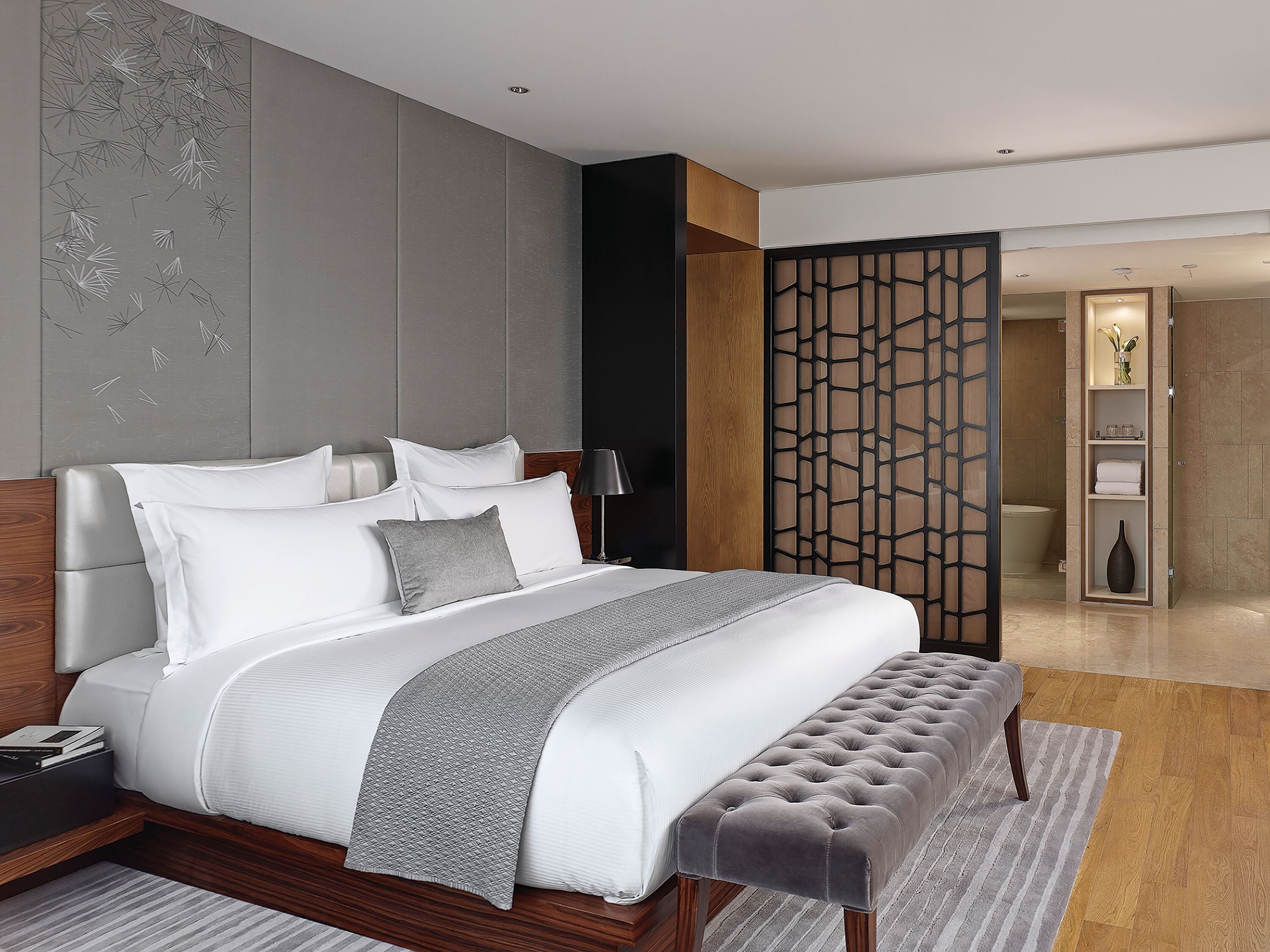 Un dormitorio moderno con una cama grande, una mesita de noche, una lámpara y un panel decorativo en la pared.