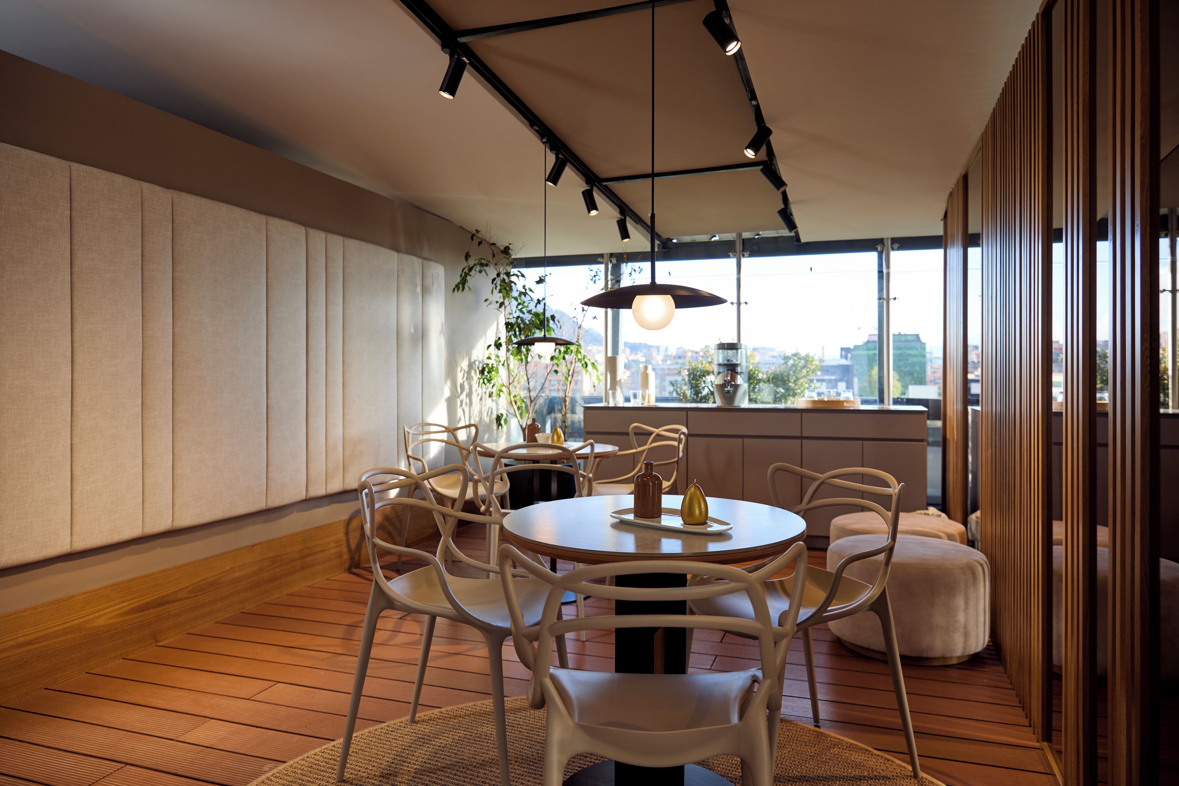 A modern dining area with a round table, white chairs, and pendant lighting.