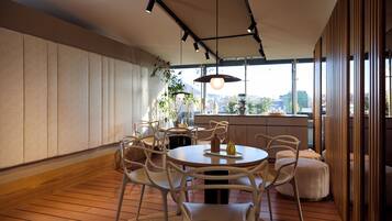 A modern dining area with a round table, white chairs, and pendant lighting.