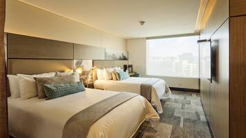 A hotel room with two beds, a large window, and a flat-screen TV.