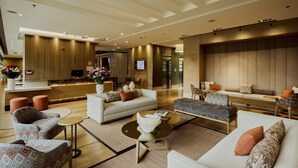 A modern hotel lobby with a reception desk, seating areas, and a large wall-mounted television. - EK Hotel By Preferred Hotels Group (Bogotá)