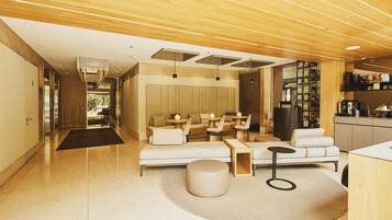 A modern interior with a sofa, round table, and a kitchen area.