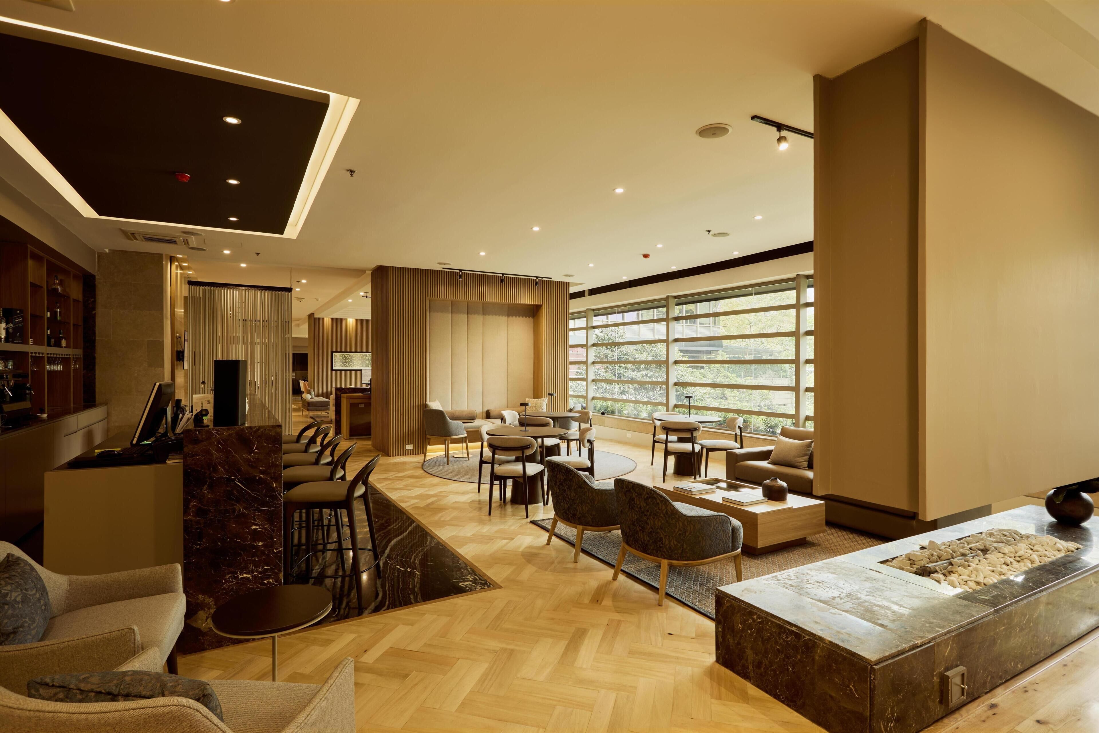A spacious lobby with a bar area, seating arrangements, and large windows providing natural light.