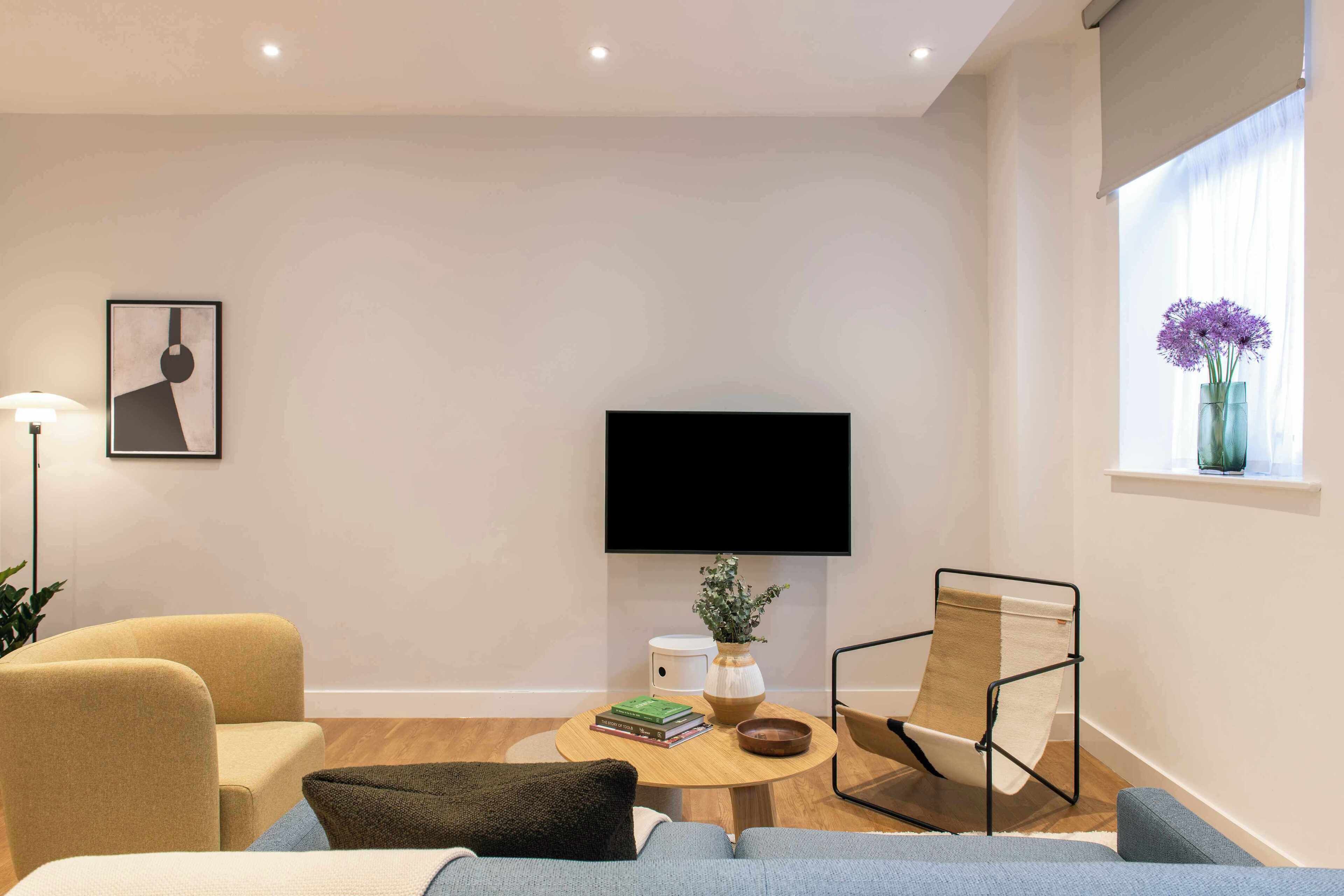 A modern living room with a sofa, armchair, and a coffee table with books and a vase.