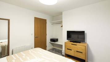 Un dormitorio con cama, cómoda de madera, televisor, armario y espejo.