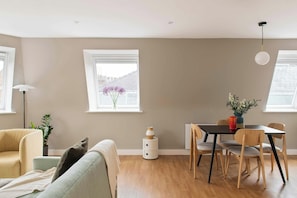 A modern living room with a sofa, dining table, chairs, and a small side table.