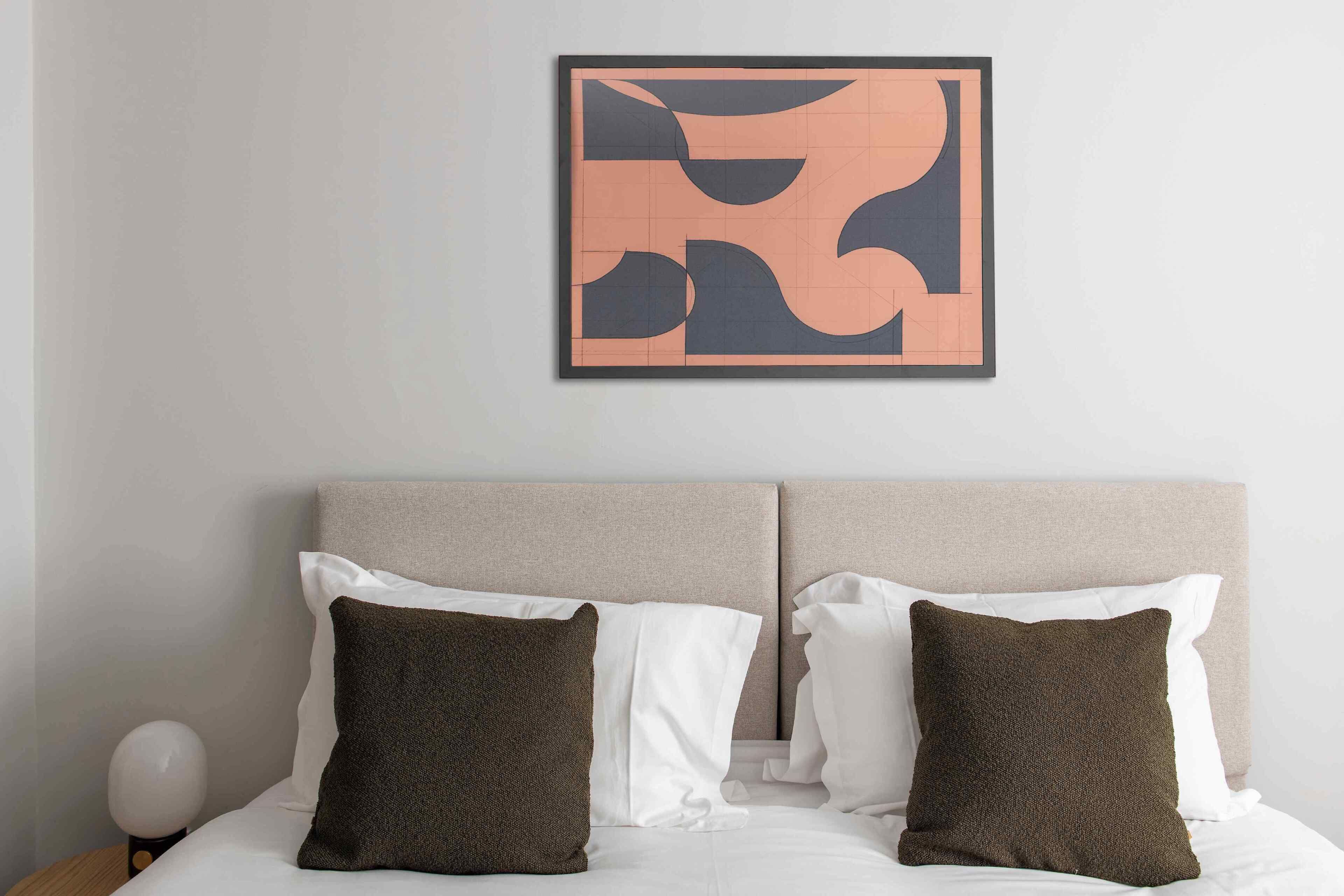 Un letto rifatto con due cuscini, una testiera e un quadro astratto appeso alla parete.