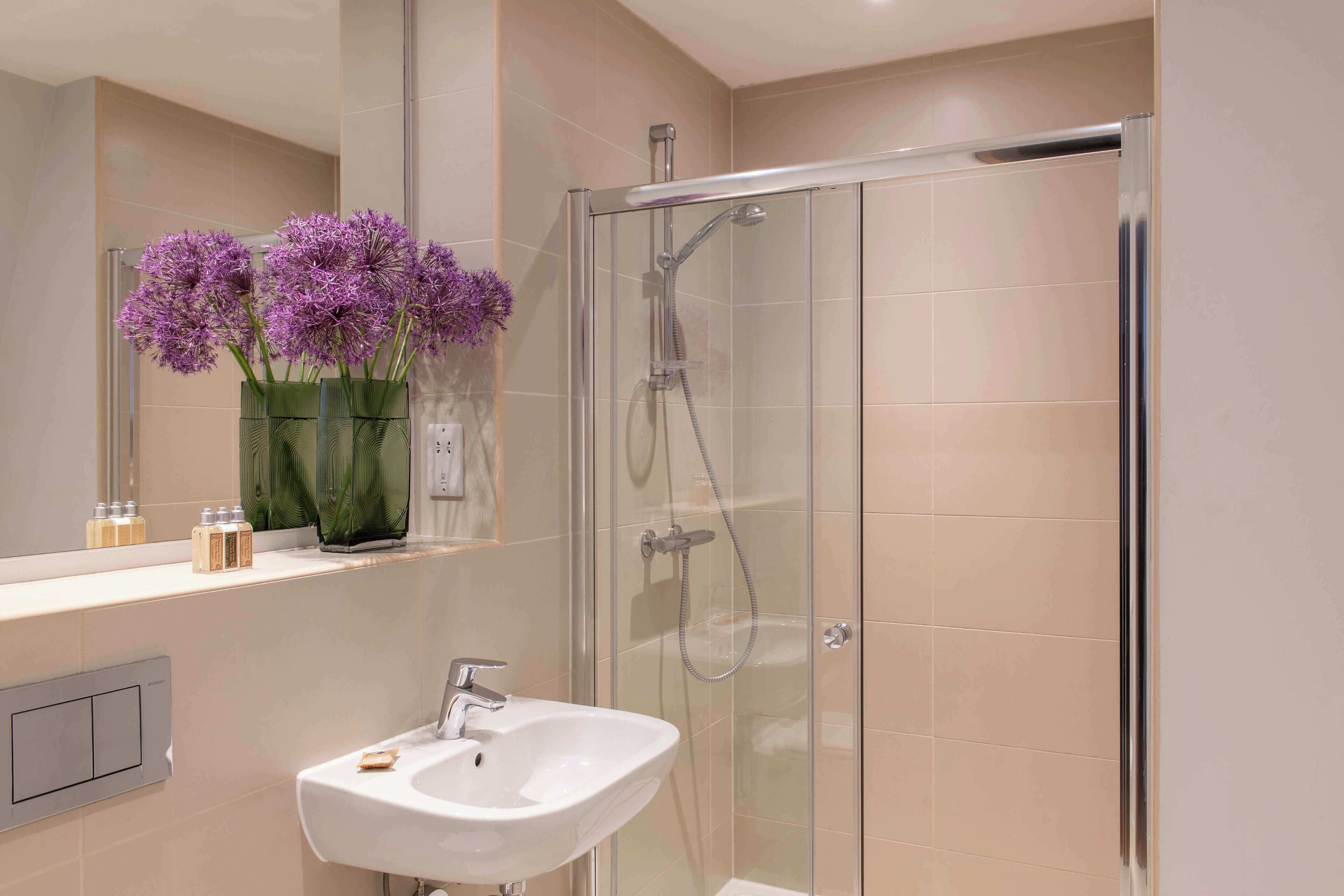 A bathroom with a glass-enclosed shower, a sink, and a mirror.