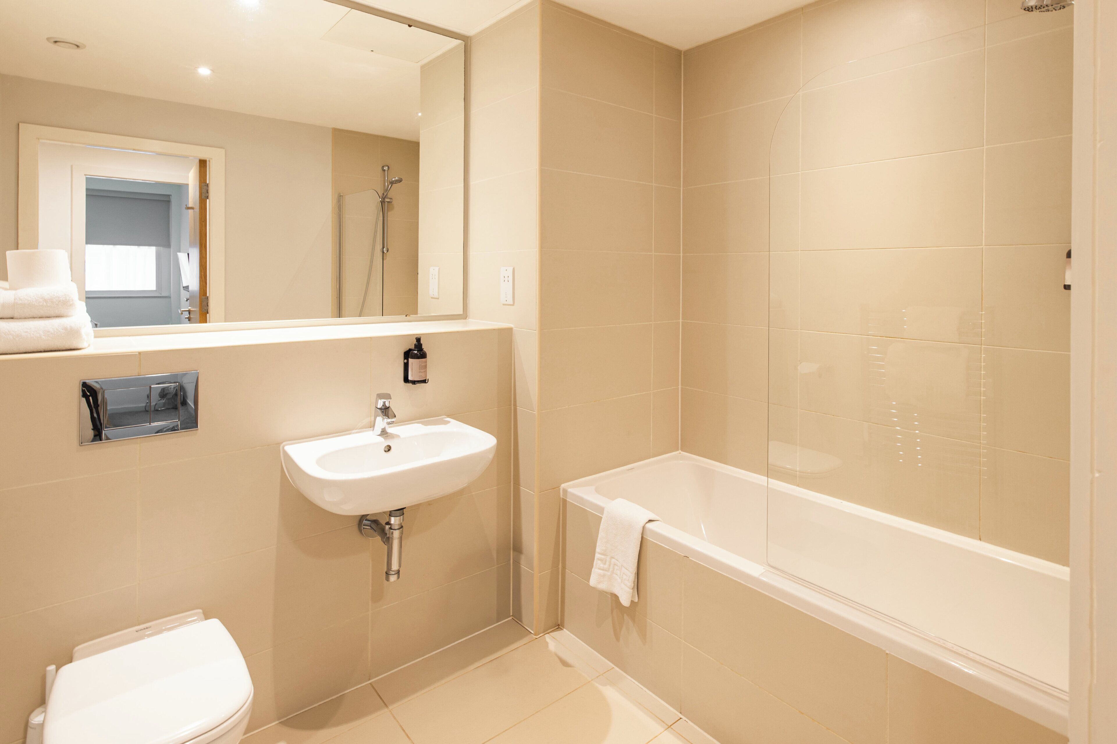 A modern bathroom with a toilet, sink, and bathtub.