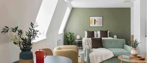 Una habitación moderna y luminosa con cama, zona de estar y mesa de comedor.
