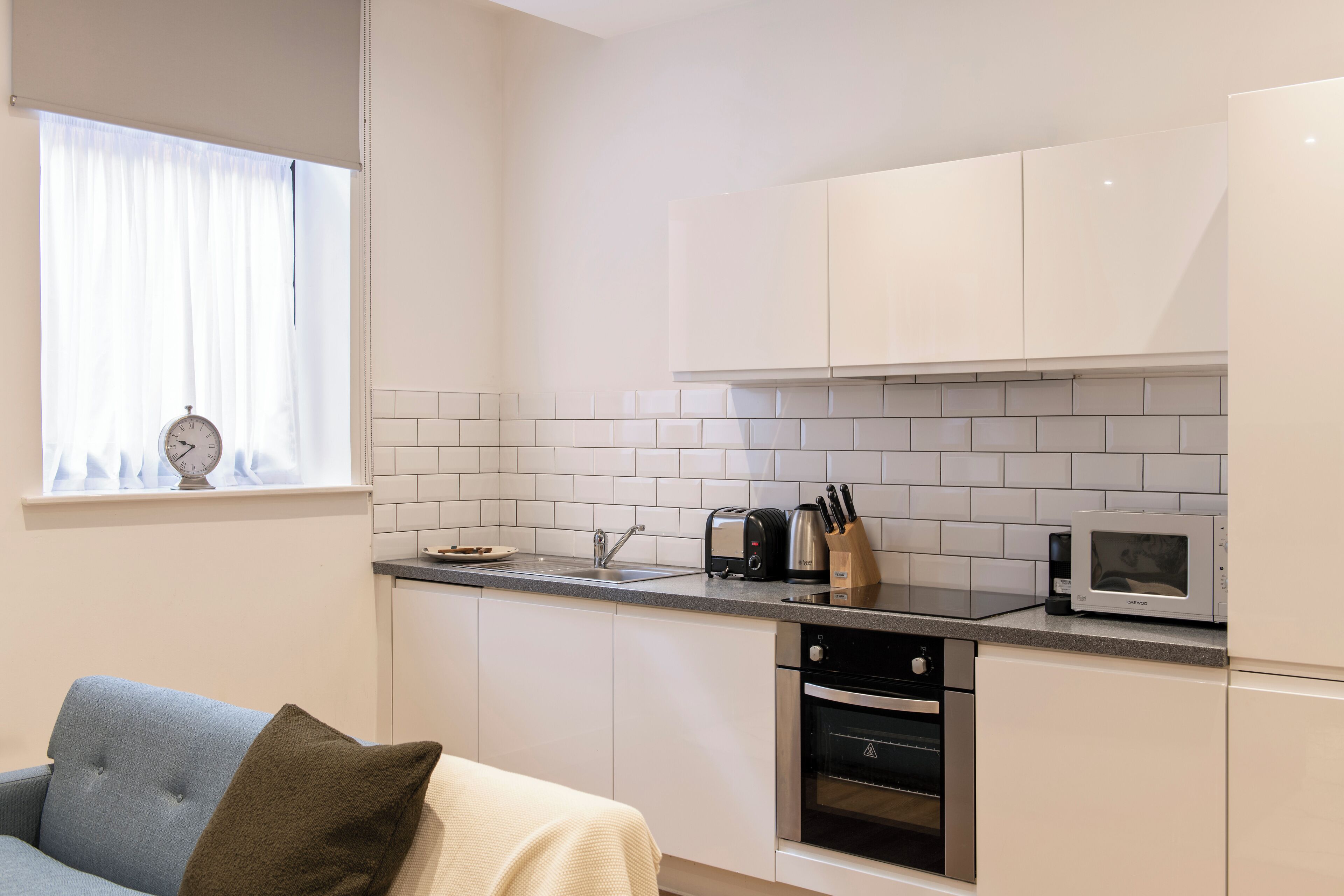 A modern kitchen with white cabinets, a microwave, a toaster, and a sink.