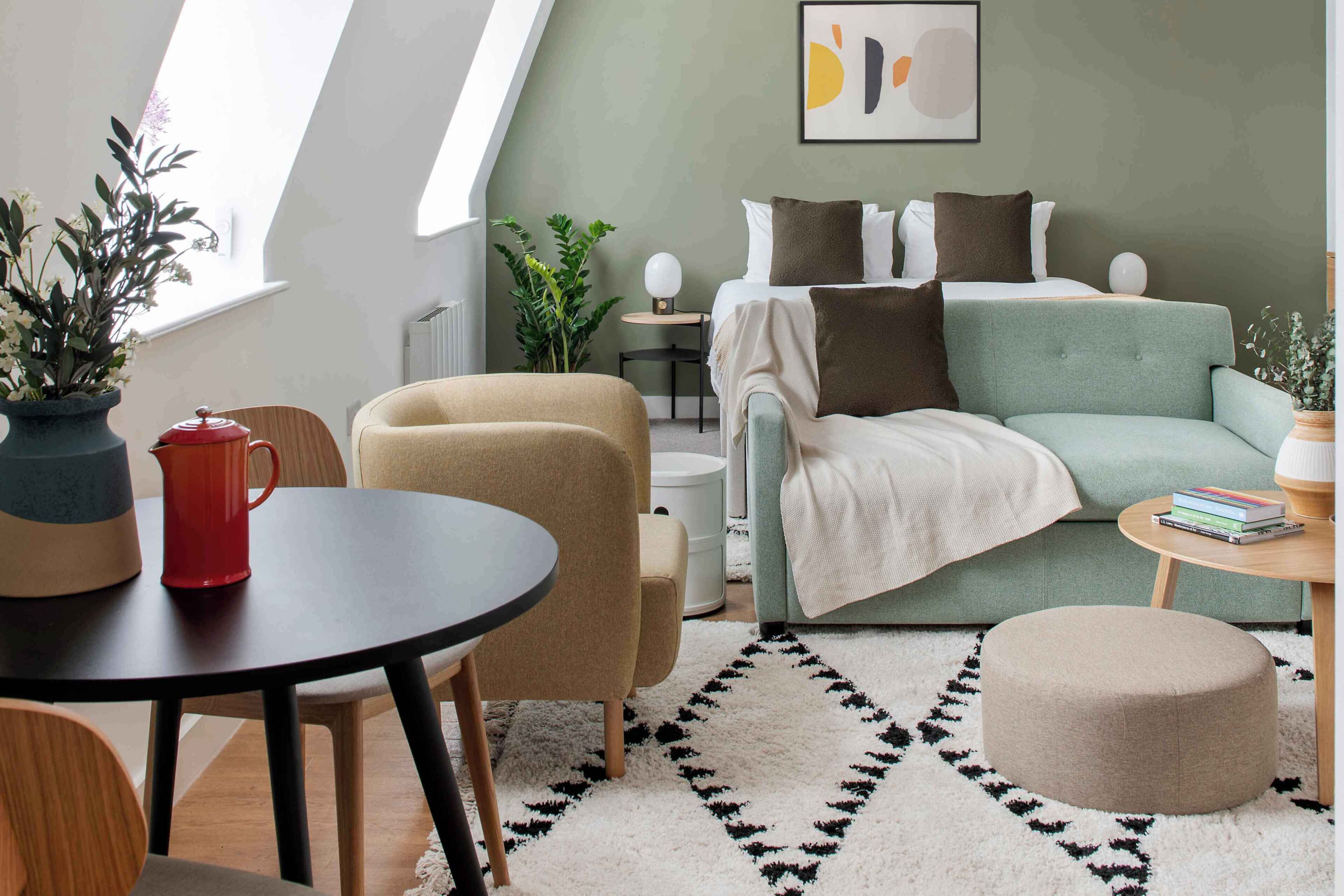 A modern living room with a sofa, ottoman, and a round table.