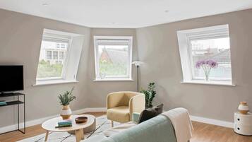 A modern living room with a television, a sofa, a chair, a coffee table, and a plant.