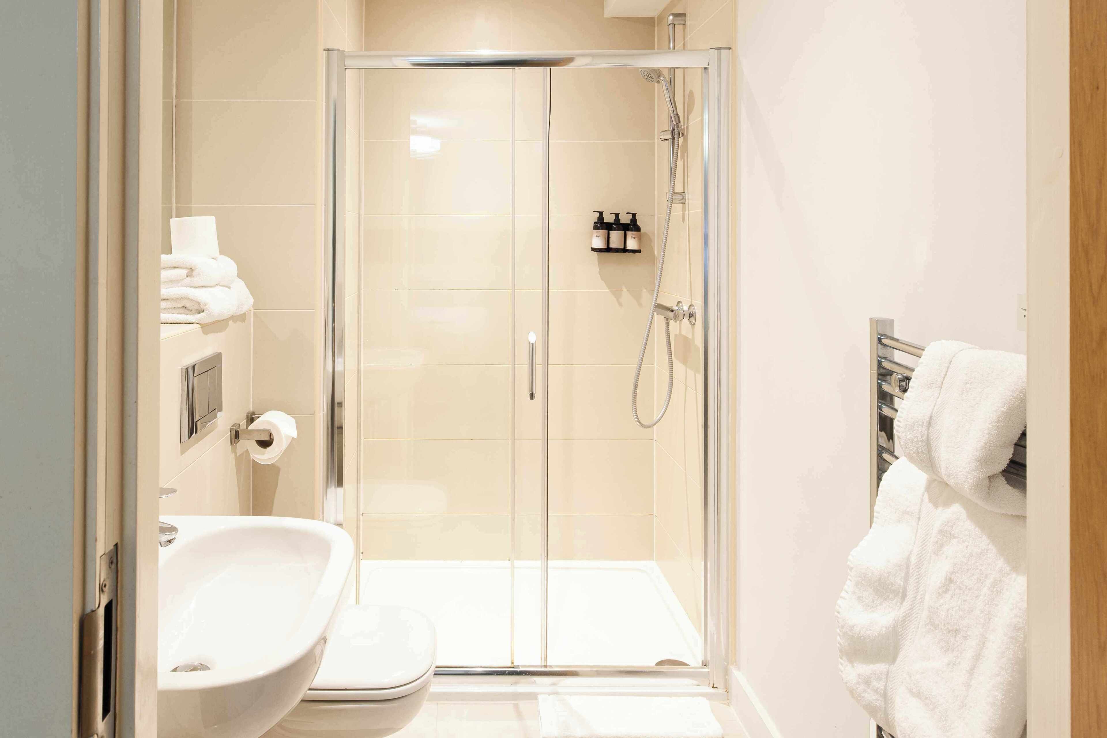 A modern bathroom with a glass-enclosed shower, a sink, and a towel rack.