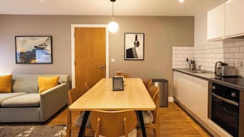 A modern kitchen with a dining table, chairs, and a coffee machine.