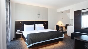 A modern hotel room with a large bed, bedside tables, a desk, and a chair.
