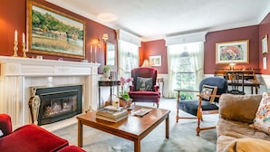 A living room with a fireplace, red and black furniture, and a painting on the wall. - Abacot Hall Bed & Breakfast (Niagara-on-the-Lake)