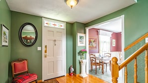 A hallway with a wooden bench, a white door with a decorative glass panel, and a staircase with a wooden railing. - Abacot Hall Bed & Breakfast (Niagara-on-the-Lake)