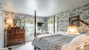 A bedroom with a four-poster bed, a wooden dresser, a vanity with a mirror, and a window with curtains. - Abacot Hall Bed & Breakfast (Niagara-on-the-Lake)