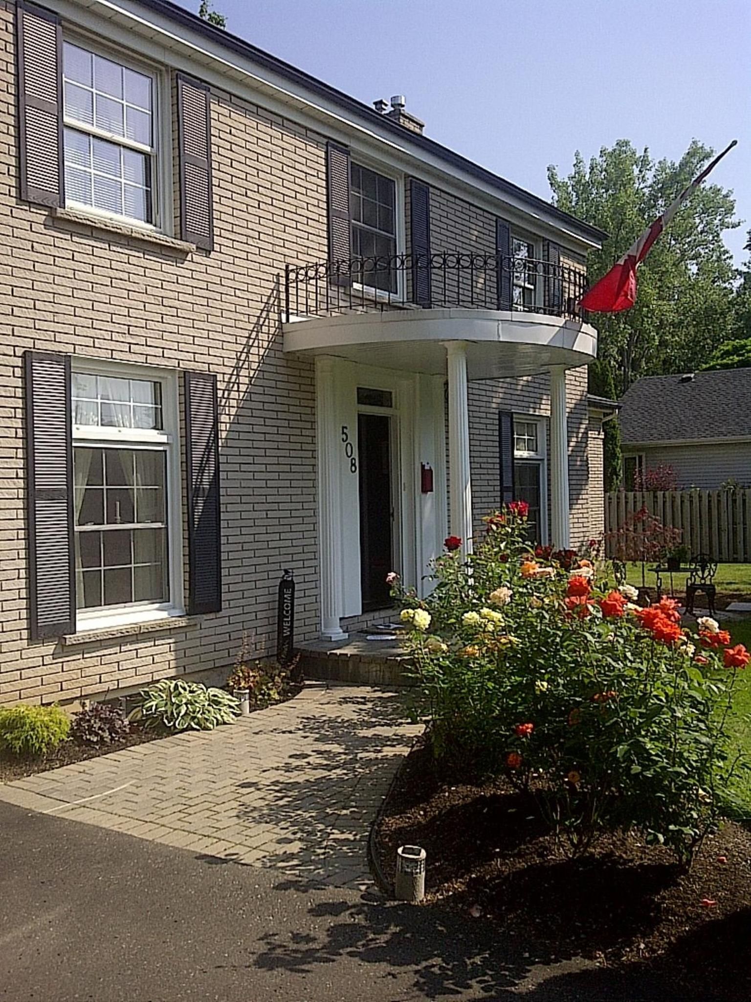 A two-story brick house with a front porch, a mailbox, and a flag.