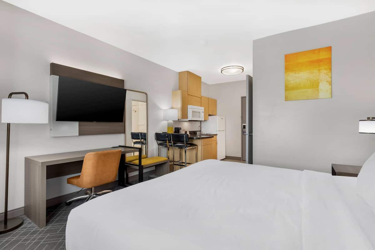 Une chambre d’hôtel équipée d’un lit, d’un bureau, de chaises, d’une télévision, d’un four à micro-ondes et d’une kitchenette.