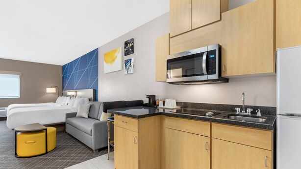 Une chambre d’hôtel moderne équipée d’une kitchenette, d’un lit, d’un canapé et d’un petit coin repas.