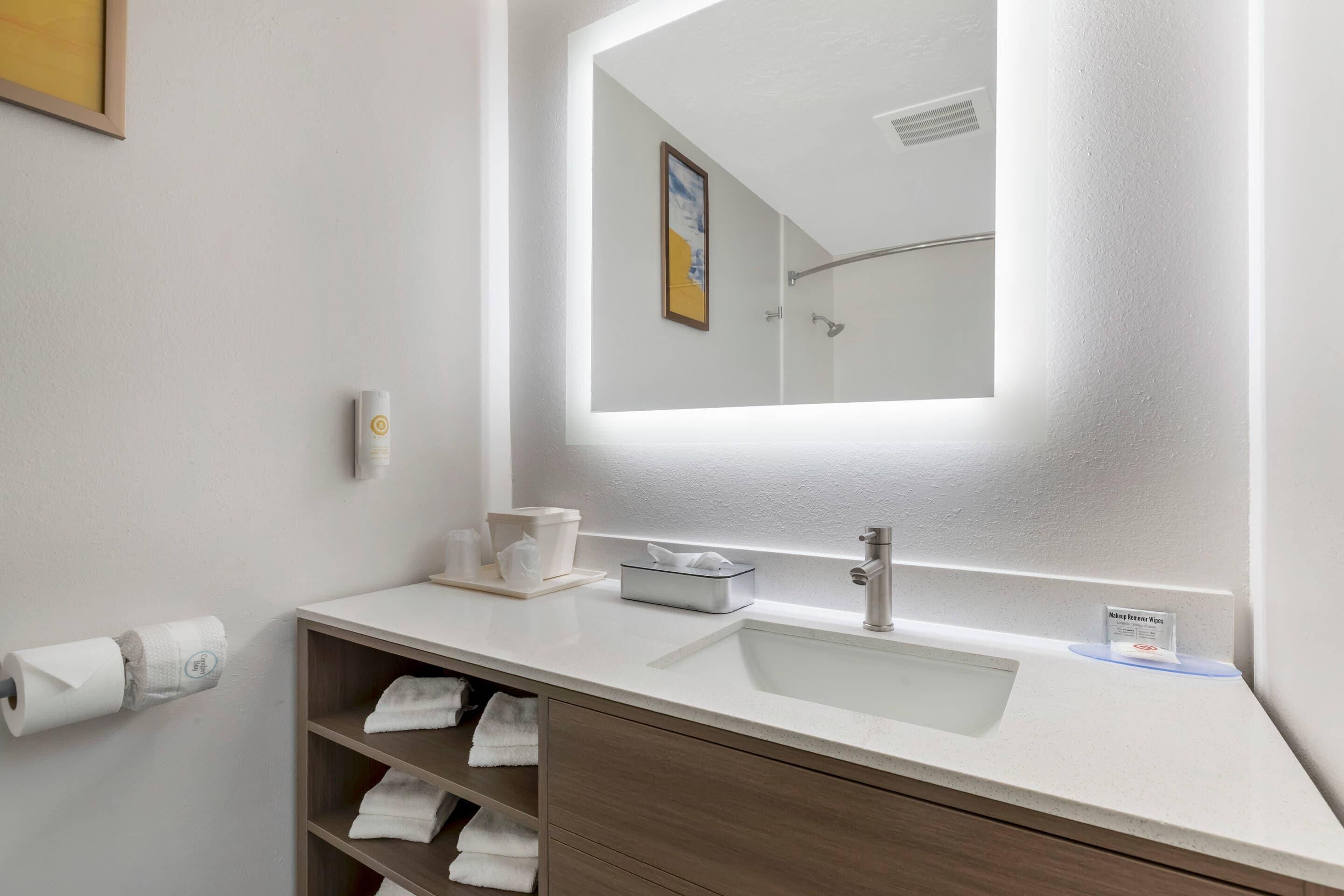 A modern bathroom with a large mirror, a sink, and a towel rack.