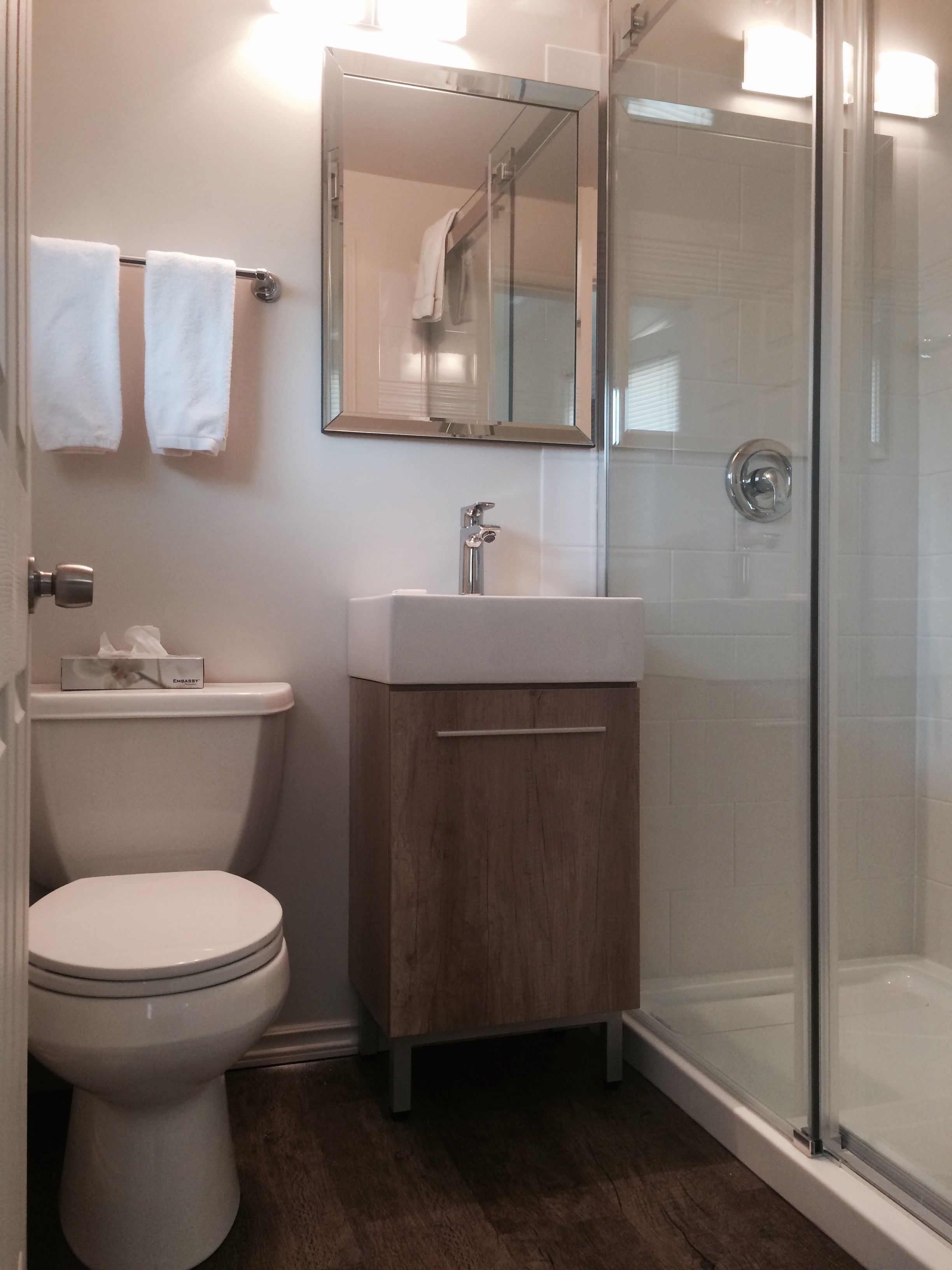 Een badkamer met toilet, wastafel en douchecabine met glazen wanden.