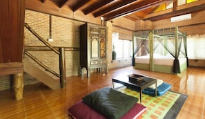 A rustic room with a wooden staircase, a bed with a canopy, and a traditional wooden cabinet.