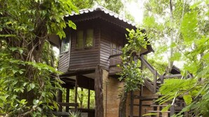 A wooden cabin with a balcony, surrounded by dense foliage. - Viva Chiang Mai (Chiang Mai)