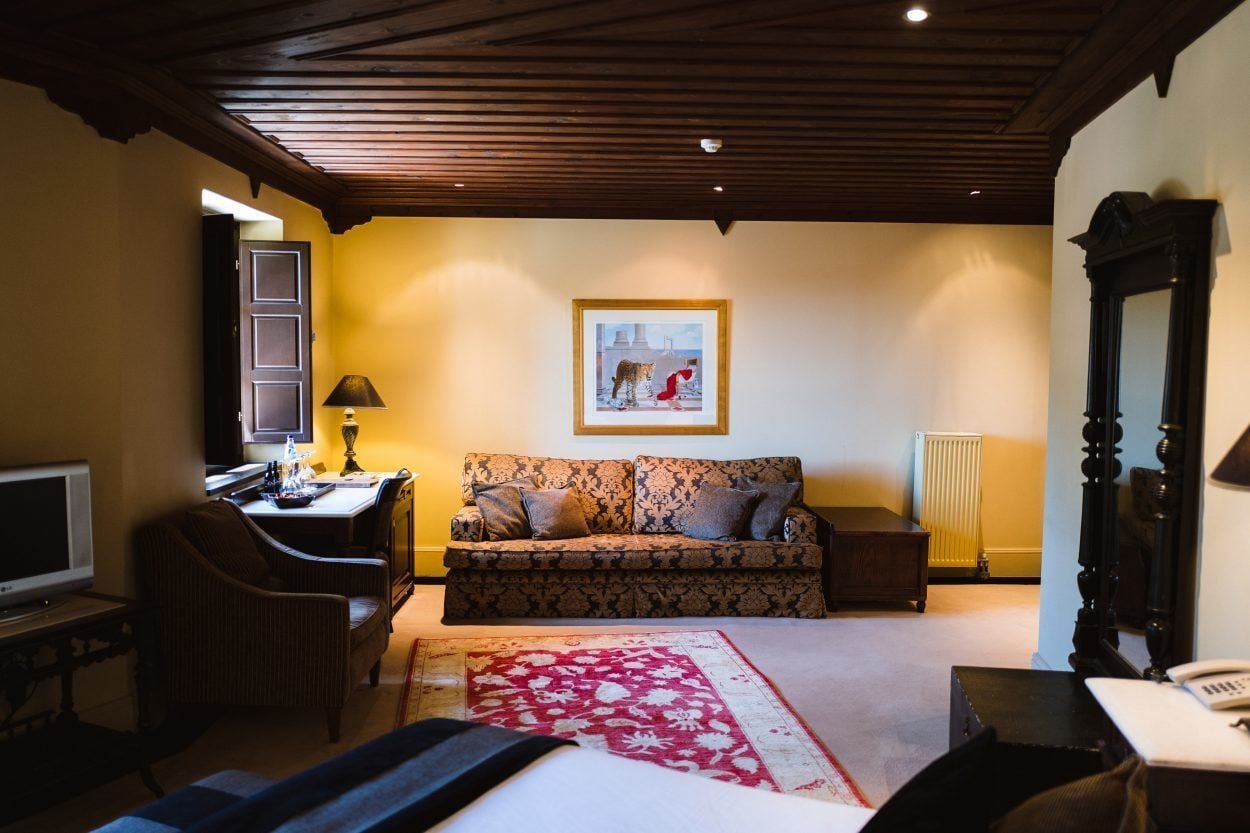 A cozy room with a sofa, a television, a desk, a lamp, and a framed picture on the wall.