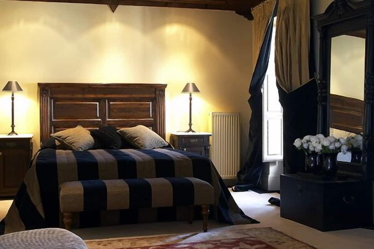 A bedroom with a large bed, two bedside tables, a dresser, and a mirror.