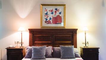 Uma cama com cabeceira de madeira, duas mesas de cabeceira com luminárias e um quadro na parede.