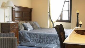 A bedroom with a bed, bedside table, lamp, chair, and window.
