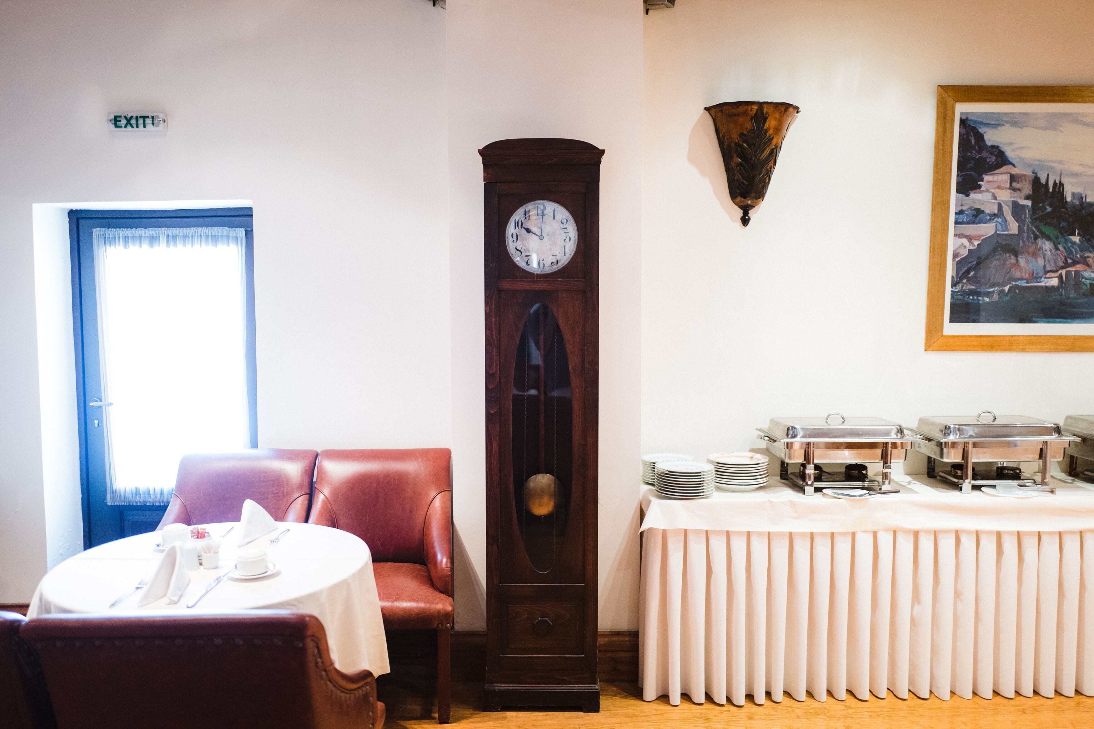 Ein Essbereich mit einer Uhr, einem Tisch mit Tellern und einem roten Stuhl.