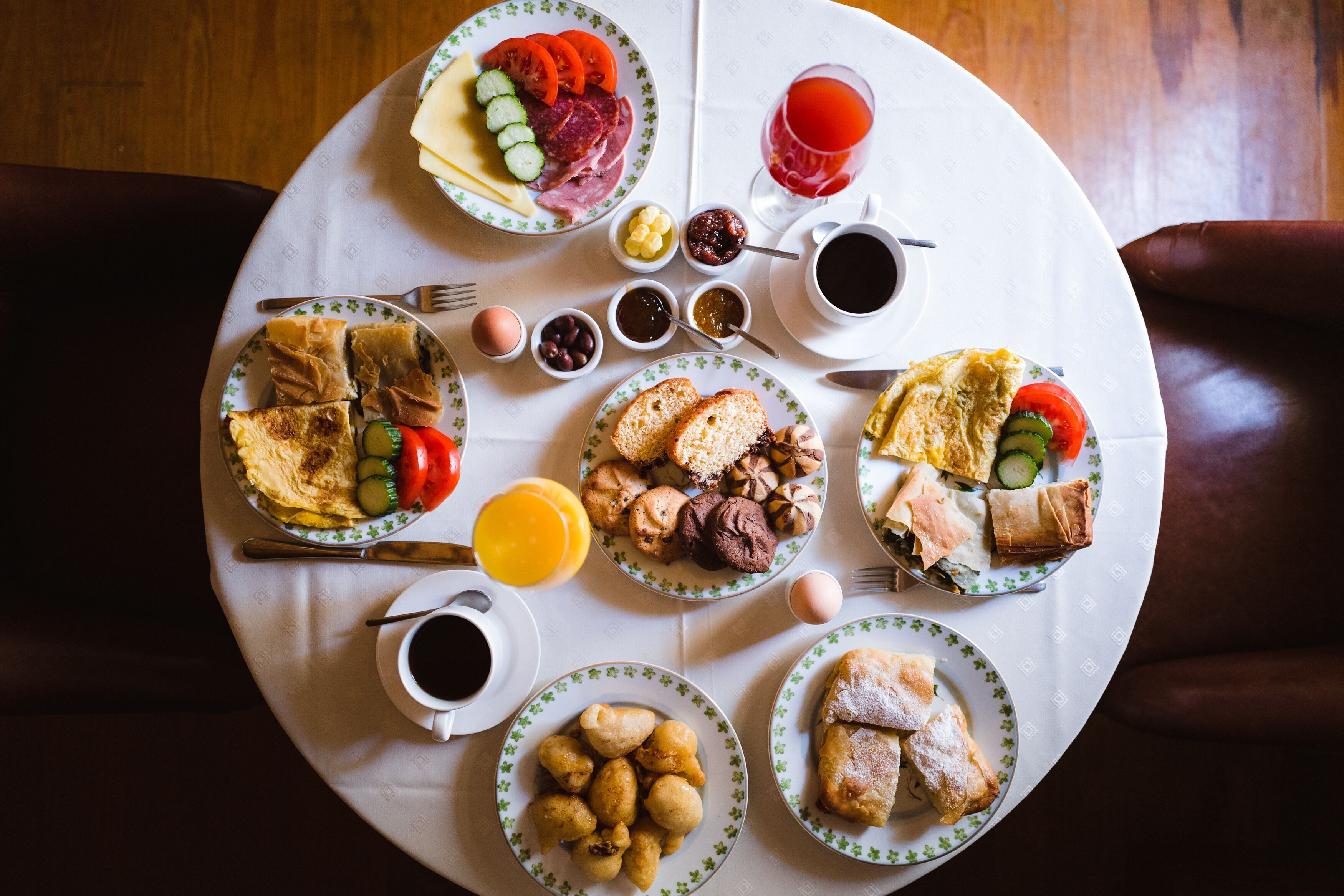 Mesa redonda para refeições com diversos itens de café da manhã, incluindo ovos, doces e frutas.