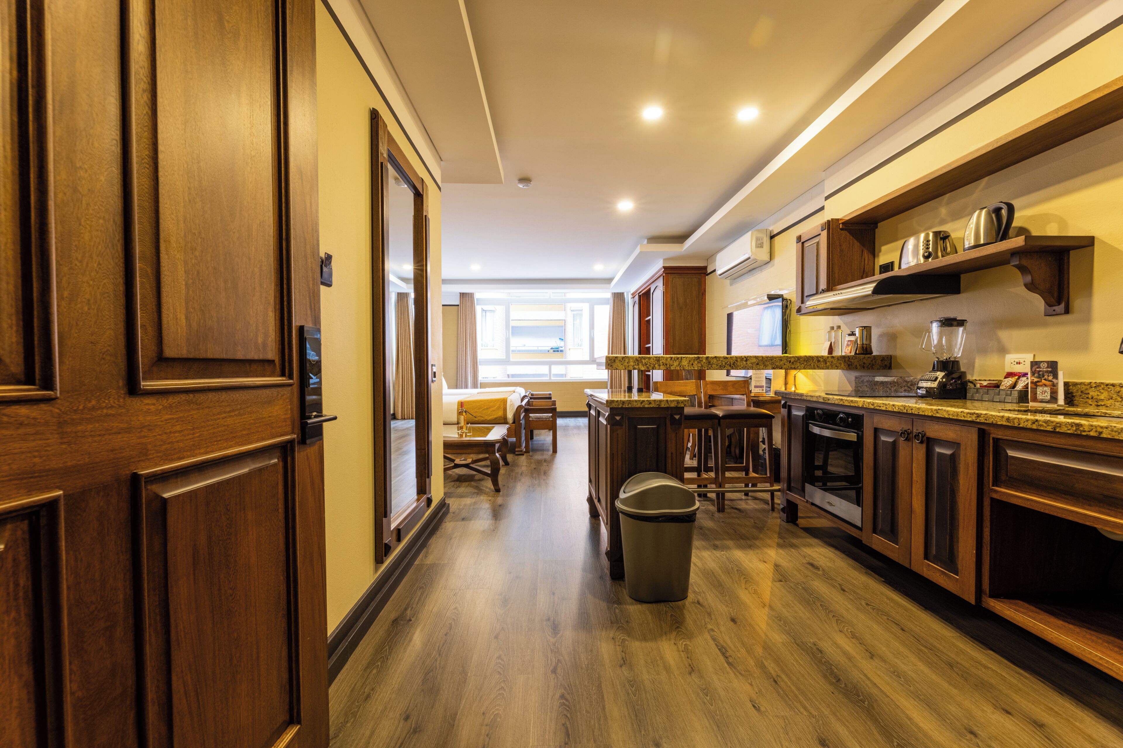A kitchen with wooden cabinets, a countertop, and a trash can.