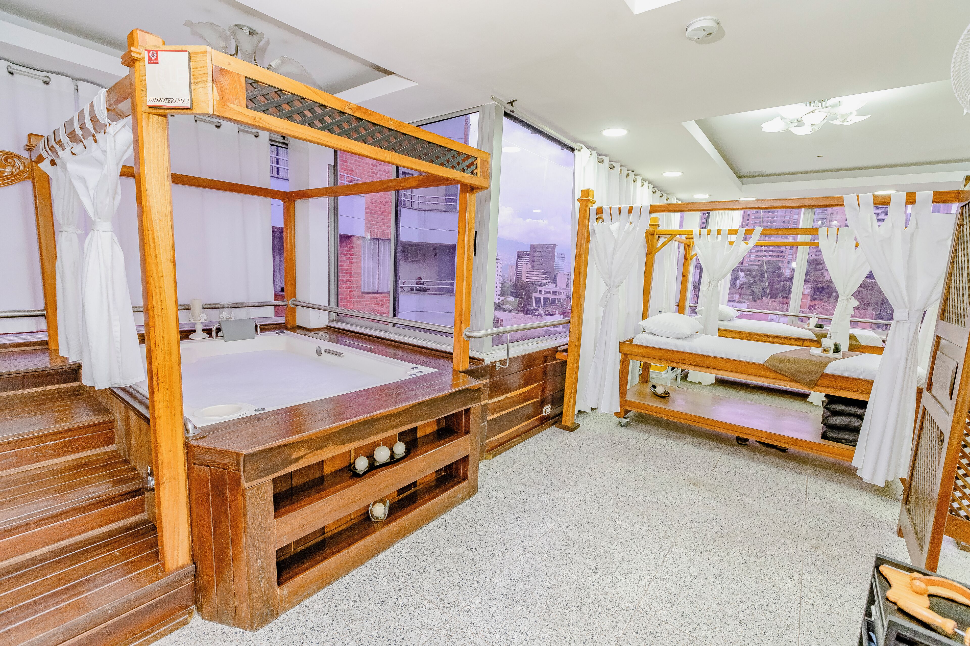 Una habitación con una cama de madera con dosel, un banco de madera y una camilla de masaje.